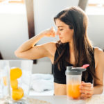 Woman At Home Drinking Orange Flavored Amino Acid Vitamin Powder
